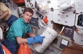 Krikalev removes a GN2 freezer from its locker on the middeck